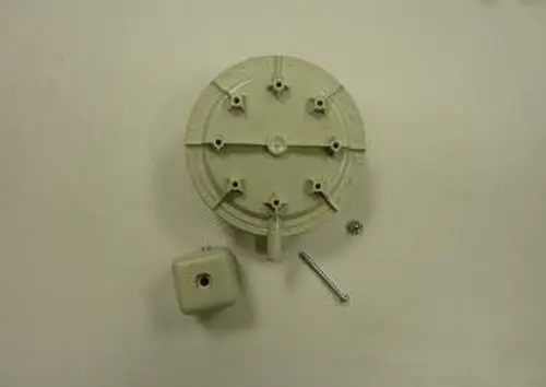 Gasdruckwächter-Set mit runder Halterung und einem kleinen quadratischen Element in heller Farbe. Zubehörteile wie Schrauben sind ebenfalls abgebildet. Remeha ist die Herstellermarke.